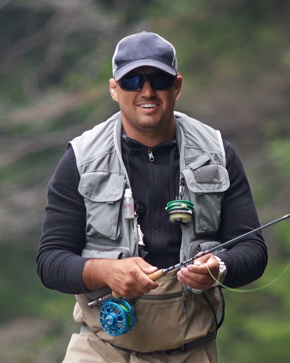 smiling fisherman holding rod while standing in ri KRL8X6N